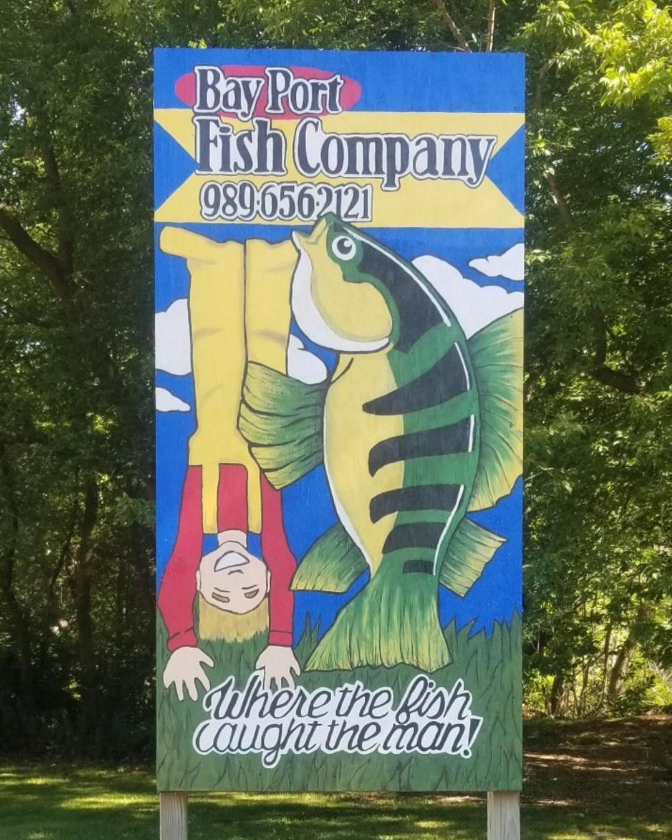 Fish caught the man Bay Port Fish Company sign.
